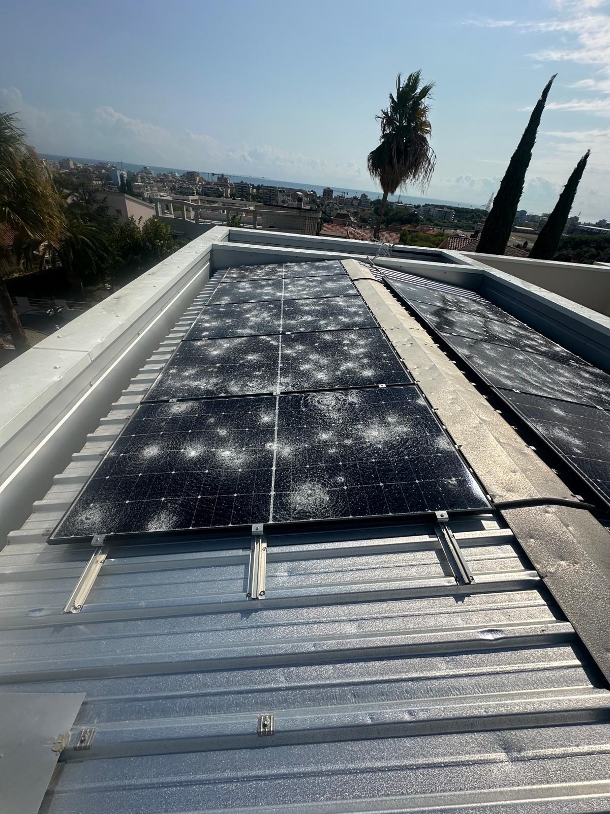 Impianto fotovoltaico di un'abitazione a San Benedetto del Tronto con pannelli sfondati dalla grandine, mare sullo sfondo