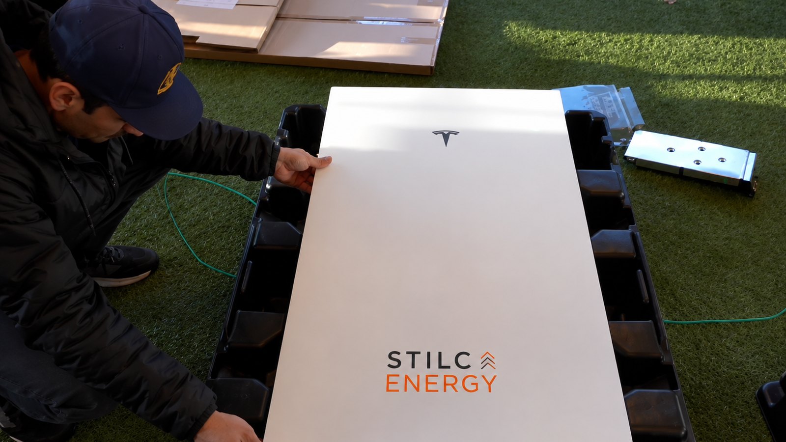 Tecnico STILCA Energy durante l'installazione di una batteria Tesla Powerwall, con il logo STILCA Energy sul pannello