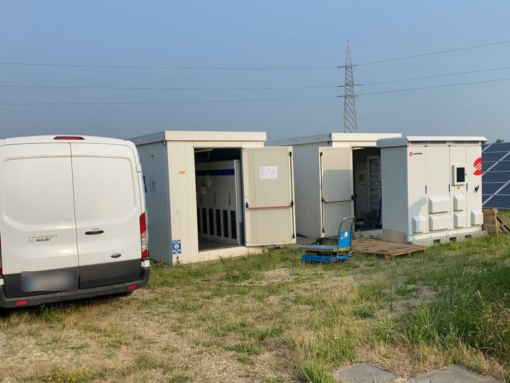 Furgone di servizio accanto alle cabine inverter aperte di un impianto fotovoltaico a terra
