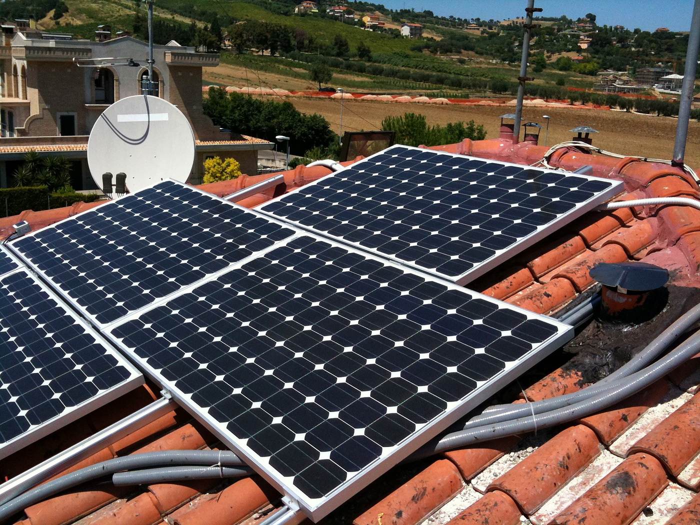Cavi dell'impianto fotovoltaico sciolti sui coppi, colmo rotto e rattoppato con malta