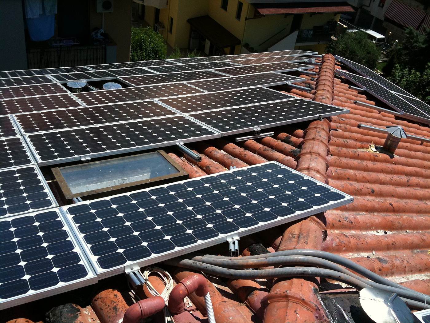 Lucernario circondato dai moduli fotovoltaici, cavi sciolti sui coppi e binari sporgenti