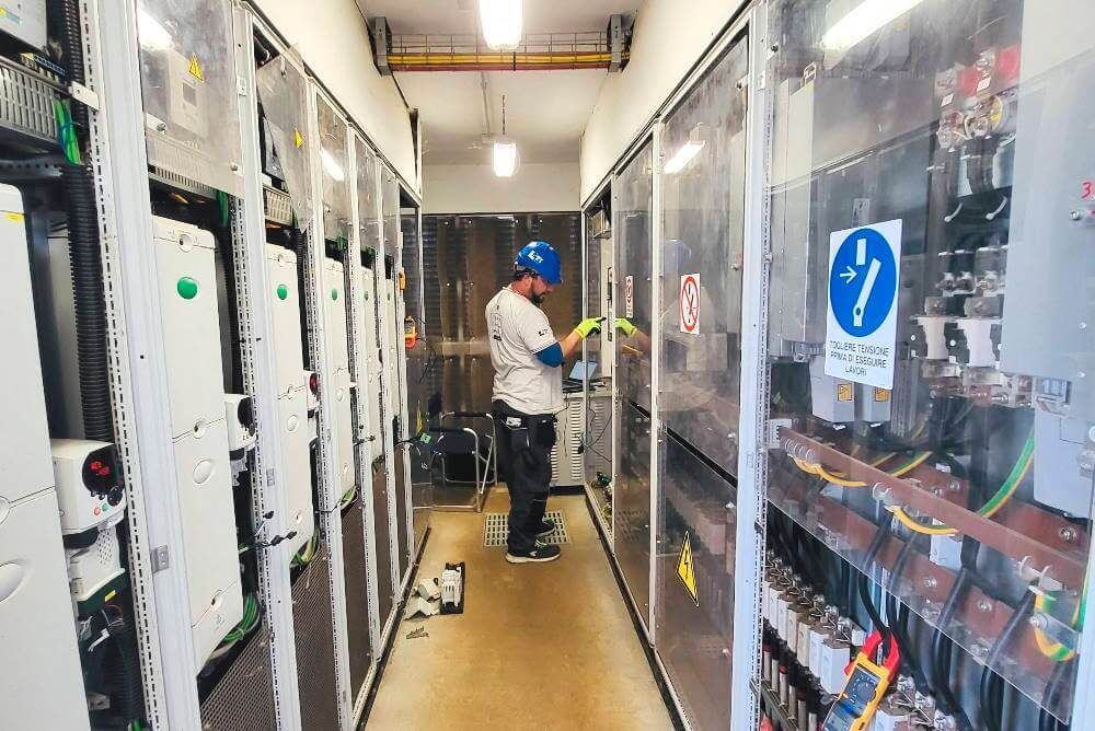 Tecnico al lavoro nella cabina inverter di un impianto fotovoltaico