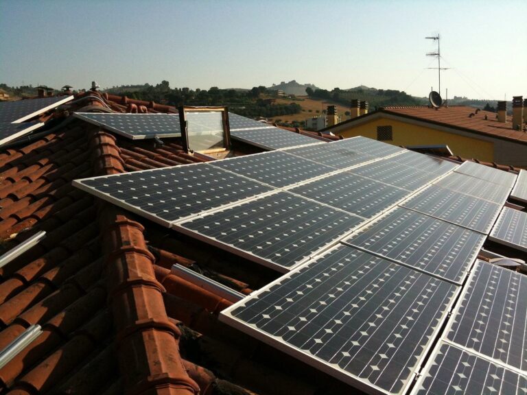 Campo fotovoltaico che scavalca i displuvi di un tetto in coppi, moduli su piani diversi