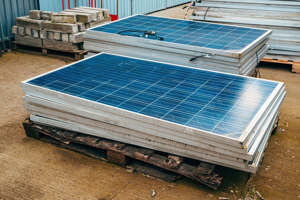 Moduli fotovoltaici dismessi impilati su pallet, pronti per il riciclo RAEE