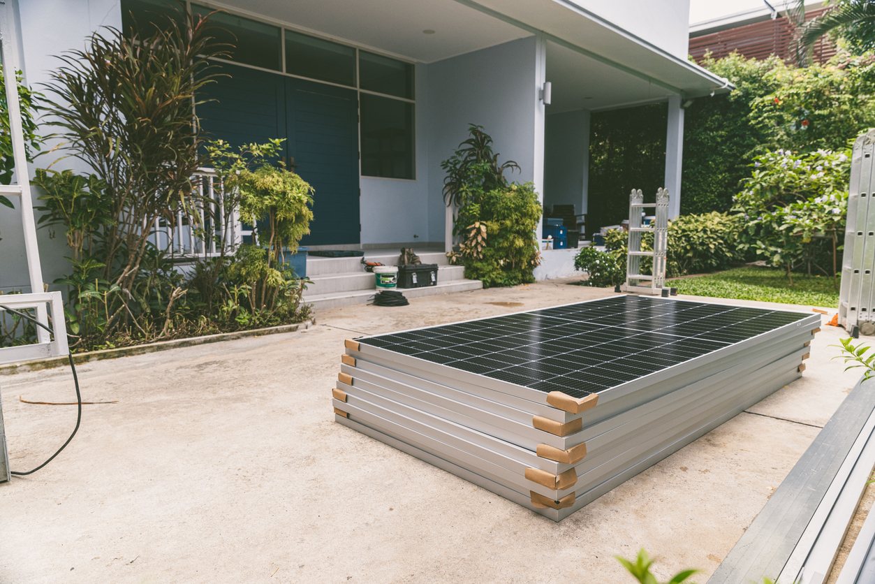 Pila di moduli fotovoltaici nuovi nel cortile di una villa, pronti per l#x27;installazione sul tetto