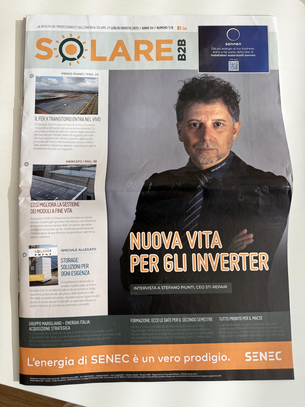 Copia cartacea di Solare B2B, luglio-agosto 2025, con la copertina «Nuova vita per gli inverter» appoggiata su una scrivania