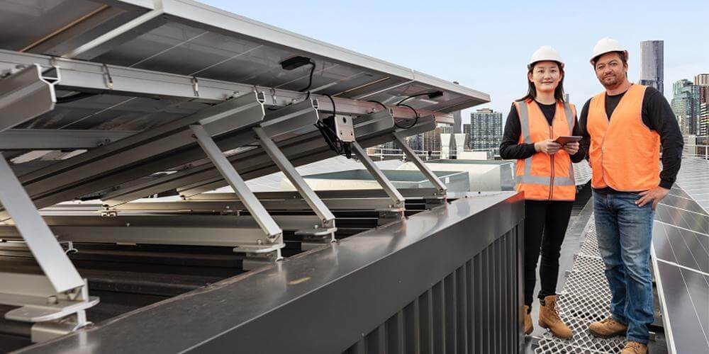 Due tecnici in copertura accanto a moduli fotovoltaici con ottimizzatore SolarEdge montato sotto il modulo