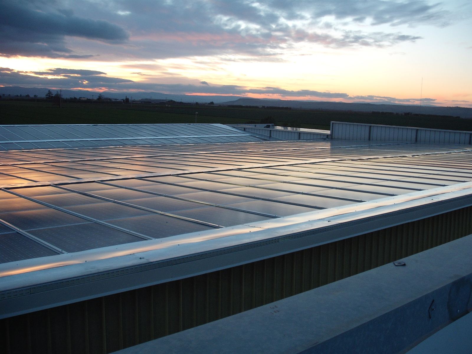 Moduli fotovoltaici su una copertura industriale al tramonto