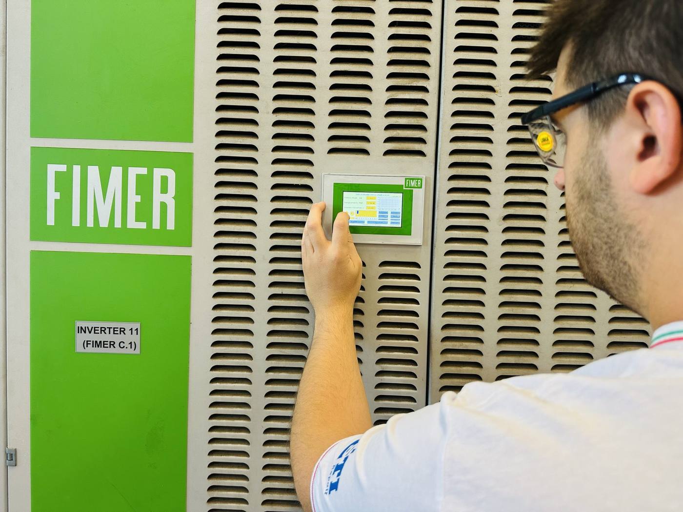 Tecnico legge il display di un inverter fotovoltaico centralizzato in cabina