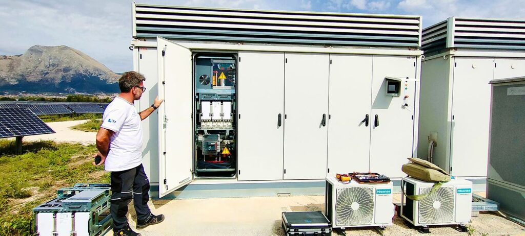Tecnico STI Repair davanti a una cabina inverter aperta in un parco fotovoltaico