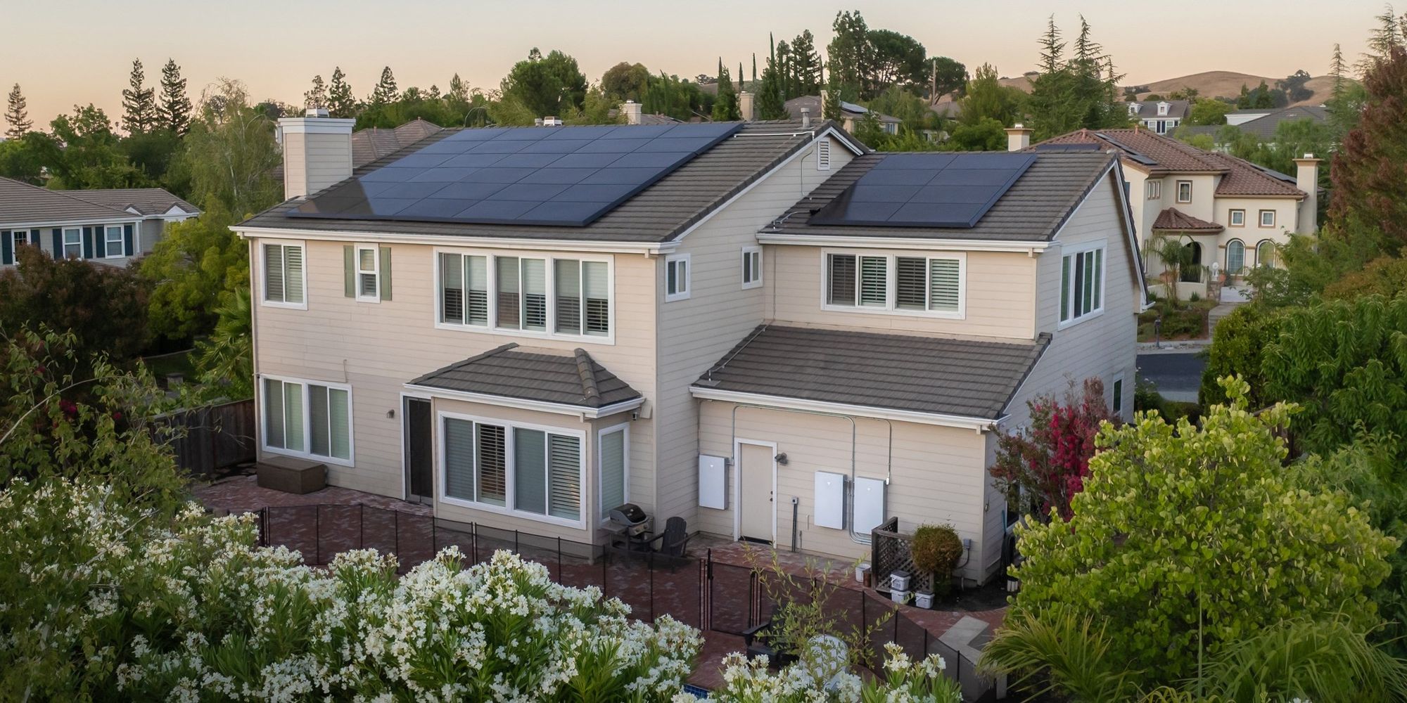 Casa contemporanea con pannelli fotovoltaici sul tetto e auto elettrica davanti al garage