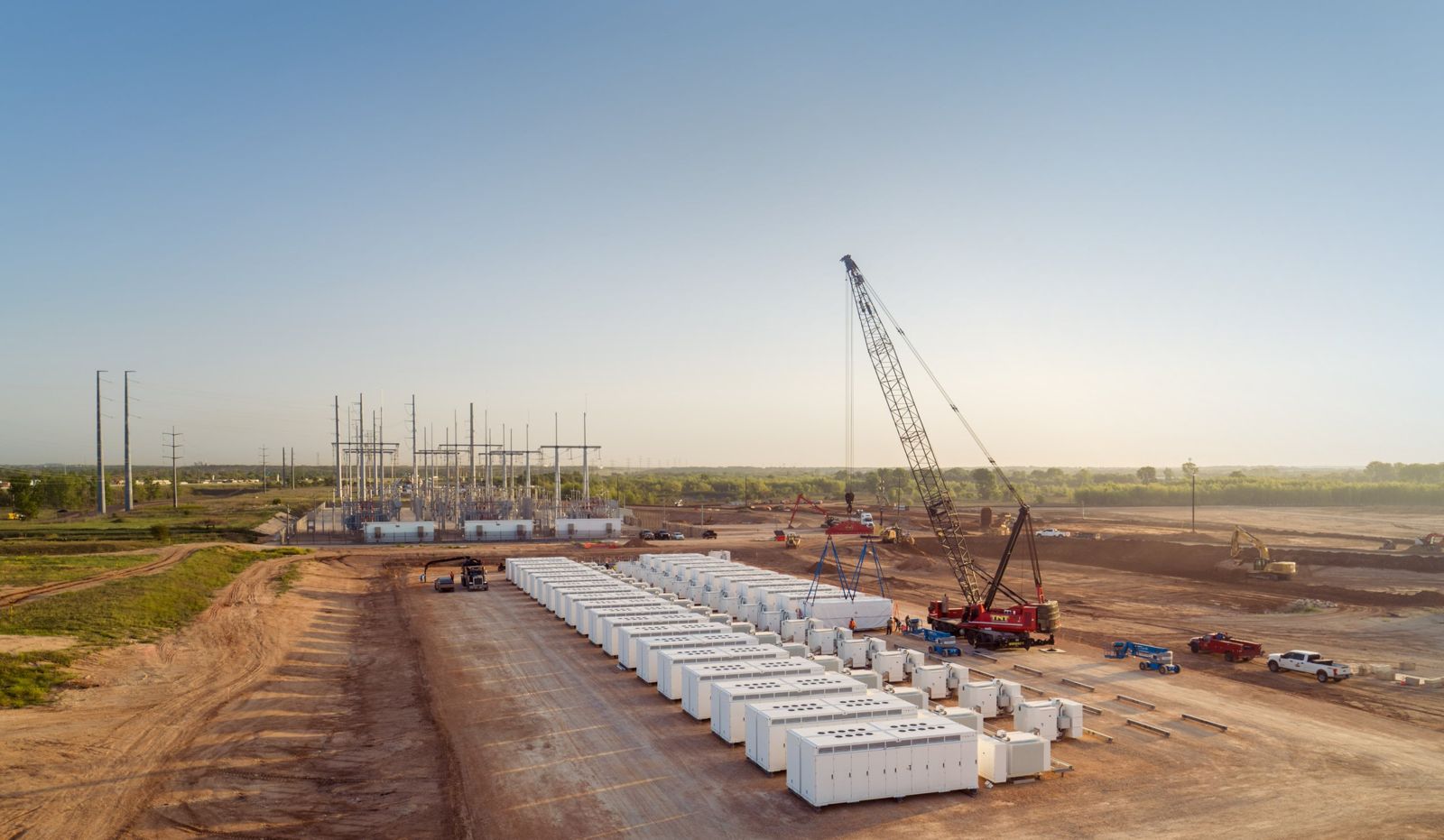 Cantiere di un impianto Tesla Megapack con unità posate in fila accanto a una sottostazione