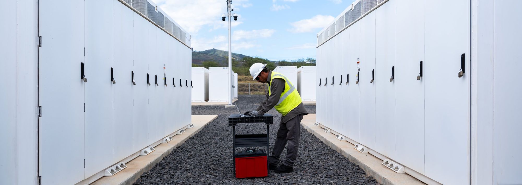Tecnico al lavoro tra due file di unità Tesla Megapack