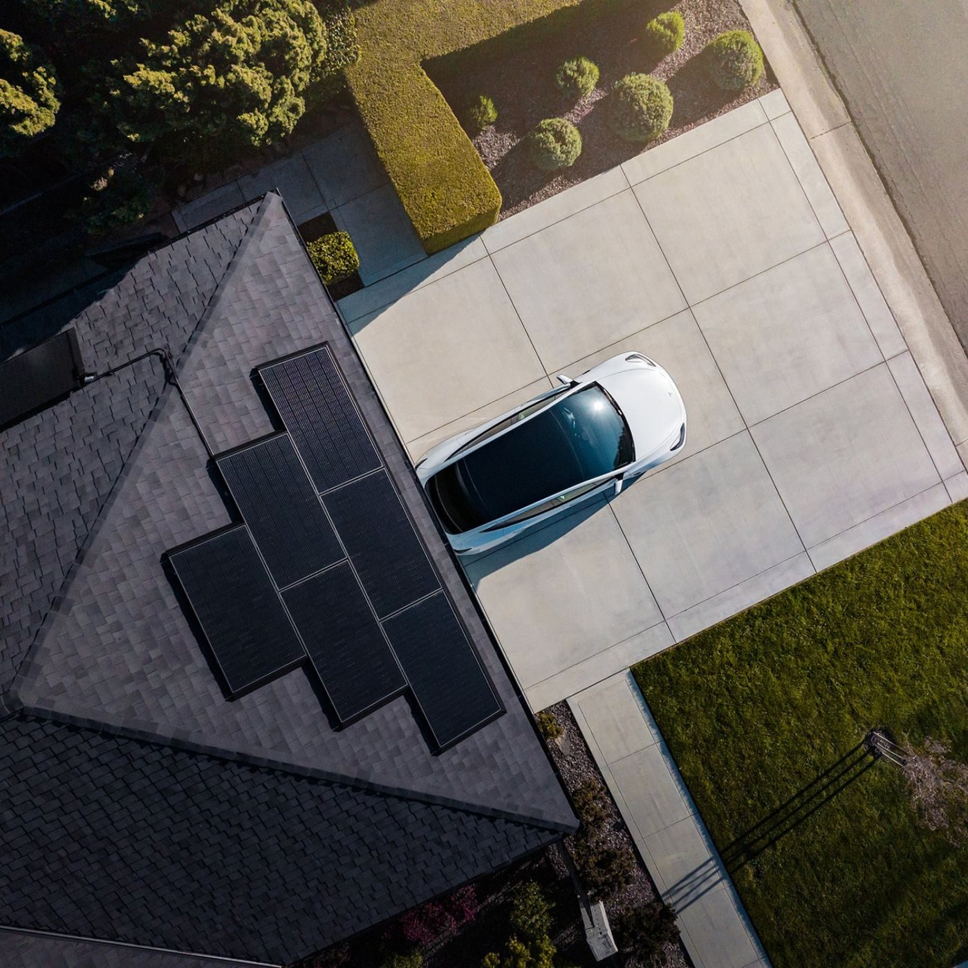 Casa vista dall'alto con pannelli fotovoltaici sul tetto e auto elettrica nel vialetto