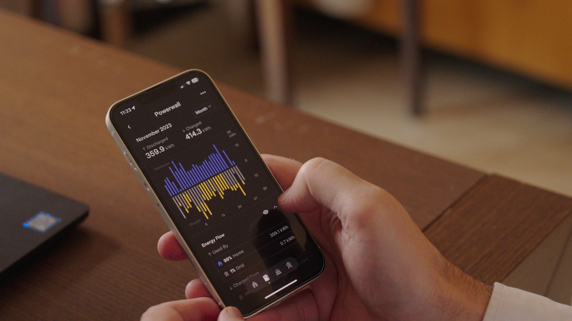 Mano che tiene lo smartphone con l'app Tesla aperta sui grafici dell'energia
