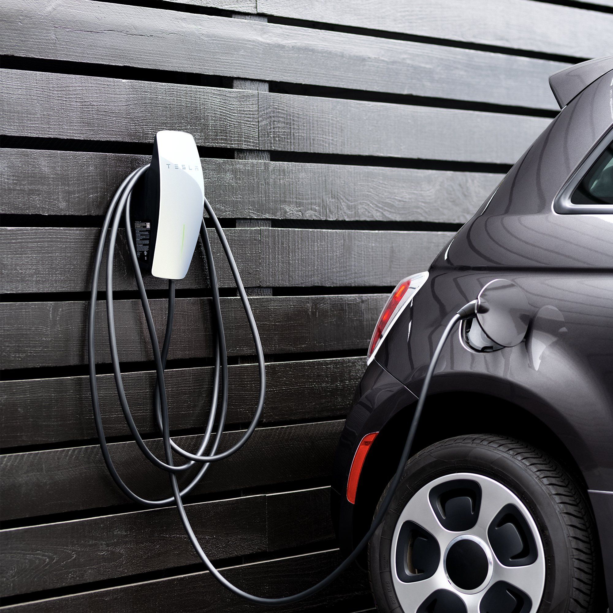 Wall Connector Tesla montato sulla parete di casa con auto in ricarica