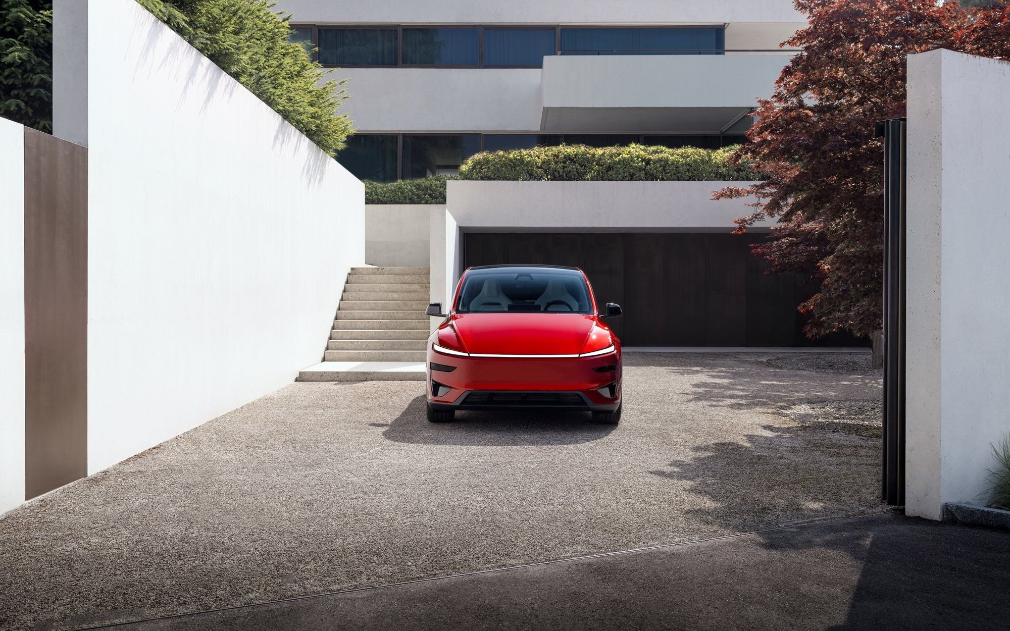 Auto Tesla rossa parcheggiata davanti a casa con Wall Connector